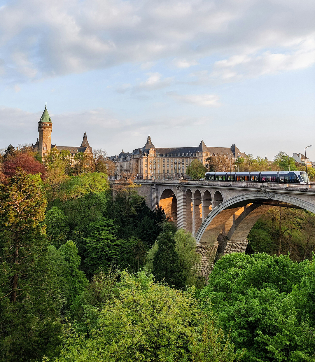 Tramvaj na znamenitem mostu Adolphe nad zeleno dolino Pétrusse v mestu Luxembourg.